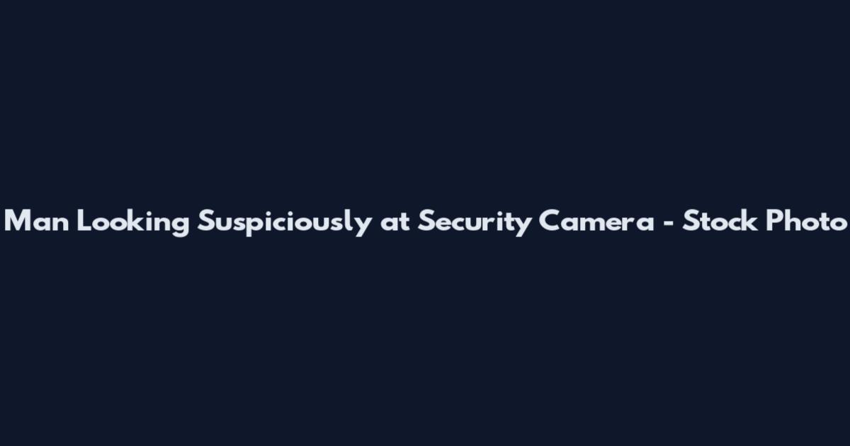 Man Looking Suspiciously at Security Camera - Stock Photo